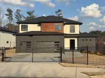 Modern two-story home featuring a brick facade, black framed windows and a two-car garage, framed by a black metal fence at 2551 Kilgore Rd, Buford, GA 30519