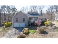 Charming exterior view of home, showing a two-car garage, complemented by a landscaped yard with blooming flowers at 523 Penny Ln, Woodstock, GA 30188