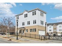 Beautiful three-story townhouse with light blue siding, brick base, black fence and a well-manicured lawn at 2000 Ocean Nw Dr, Atlanta, GA 30318