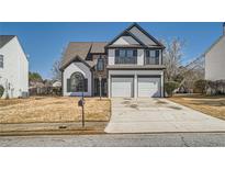 Charming two-story home with a two-car garage and manicured front yard on a sunny day at 3291 Quincey Xing, Conyers, GA 30013