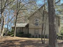 Two story home with neutral siding and mature trees in the front yard, creating a private setting at 3335 New Heritage Dr, Johns Creek, GA 30022