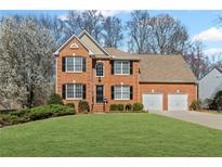 Charming two-story red brick home featuring a manicured lawn, black shutters and a two car garage at 1760 Clayton Cir, Cumming, GA 30040