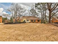 Charming single-story home with a brick facade, yellow trim, and well-manicured lawn at 573 Ripplewater Sw Dr, Marietta, GA 30064