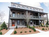 Charming three-story townhome boasts a brick facade, balcony and inviting orange front door at 6505 Cortland Walk, Alpharetta, GA 30005