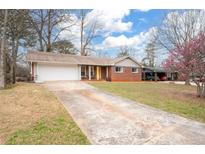 Charming brick home featuring a long driveway and a well-manicured lawn at 3890 Cherrydale Se Ln, Smyrna, GA 30082