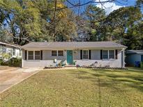 Charming single-story home featuring a brick facade, teal door, and well-maintained lawn with mature trees at 1824 Evans Sw Dr, Atlanta, GA 30310