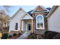 Charming front entrance with stone and stucco exterior, featuring a covered porch and landscaped garden at 3619 Elinburg Ne Ct, Buford, GA 30519