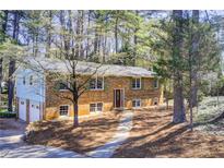 Traditional brick home with a two-car garage and mature trees in a serene, wooded setting at 410 Killian Hill Sw Rd, Lilburn, GA 30047