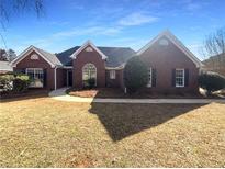 Traditional brick home with a well-maintained front yard on a sunny day at 2979 Orchard Sw Rd, Conyers, GA 30094
