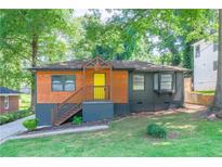 Charming home featuring a colorful front door, wood accents, and a well-maintained lawn with mature trees at 1251 Richland Sw Rd, Atlanta, GA 30310