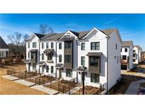 Stunning three-story townhome featuring brick facade, sleek black windows, and professional landscaping at 504 Healy Dr # 75, Cumming, GA 30040
