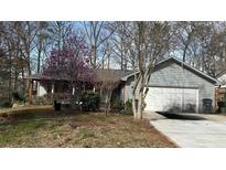 Charming one-story home featuring an attached garage and a well-maintained front yard with flowering trees at 1302 Buttercup Ct, Lawrenceville, GA 30044