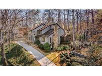 Charming two-story home with stone chimney, lush landscaping, and a screened porch nestled in a wooded lot at 6055 Blackwater Trl, Atlanta, GA 30328