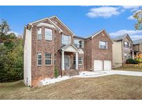 Two-story brick home featuring a two-car garage, a manicured lawn, and mature trees at 2725 Palmview Sw Ct, Atlanta, GA 30331