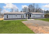 Charming single-story home with gray siding, stone accents, green lawn and gravel driveway at 3696 Lower Burris Rd, Canton, GA 30114