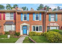 Charming brick townhome featuring colorful shutters, a bright blue door with wreath, and manicured front yard at 6105 Queen Anne Ct, Norcross, GA 30093