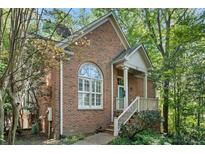 Charming brick home featuring a quaint porch with a stairway entrance and lush surrounding greenery at 31 Greenland Trce, Atlanta, GA 30342