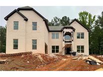 An unfinished two-story home with a brick facade and dark trim, set on a lot with trees in the background at 206 Lotus Ln, Covington, GA 30016