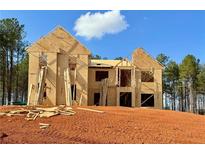 Exterior view of a new two-story home under construction on a large lot with wooded backdrop and blue skies at 218 Lotus Ln, Covington, GA 30016