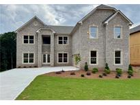 Stunning two-story brick home featuring a manicured lawn, a long driveway, and a welcoming double door entrance at 255 Lotus Ln, Covington, GA 30016