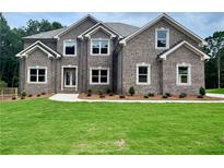 Charming two-story brick home featuring a manicured lawn and multiple windows for abundant natural light at 211 Lotus Ln, Covington, GA 30016