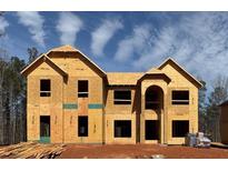 Two-story new construction home showcasing the facade with visible framing and arched entryway against a bright, partly cloudy sky at 3118 Old Covington Rd, Conyers, GA 30013