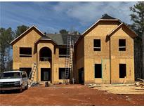 Two story new construction featuring an arched doorway and ladder to the roof at 3128 Old Covington Hwy, Covington, GA 30014