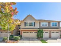 Charming townhome with two-car garage and well-maintained landscaping, offering a welcoming curb appeal at 2297 Elmbridge Rd, Buford, GA 30519