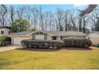 Ranch home with a brick facade, manicured shrubs, a one-car garage and a well-maintained front lawn at 4063 Elmscourt Dr, Stone Mountain, GA 30083