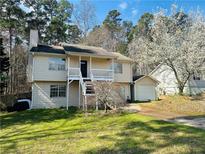 Split level home featuring a lush green lawn and a separate garage space at 3170 Ashly Brooke Dr, Snellville, GA 30078