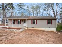 Charming ranch-style home featuring neutral siding and red shutters, nestled among mature trees at 5700 Tracy Dr, Mableton, GA 30126