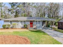 Charming one-story home featuring a red front door, gray exterior, landscaped yard, and covered carport at 3164 Robin Rd, Decatur, GA 30032