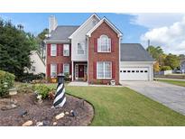 Charming two-story brick home featuring a well-manicured lawn, red shutters and attached garage at 2000 Spicers Ln, Woodstock, GA 30189