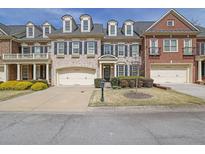 Charming townhome with manicured lawn, two-car garage, and beautiful brick and siding exterior at 7467 Portbury Park Ln, Suwanee, GA 30024