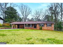 Charming brick home featuring a covered carport and a spacious front yard, perfect for outdoor activities at 422 Derbyshire Dr, Stone Mountain, GA 30088
