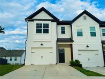 Charming townhome featuring a two-car garage, black roofline and a well-maintained front lawn at 124 Auburn Run Ln, Auburn, GA 30011