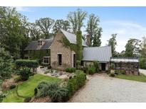 A luxurious stone home with a metal roof, greenhouse, and expertly manicured landscaping at 7455 Old Rico Rd, Chattahoochee Hills, GA 30268