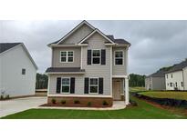 Charming two-story home with gray siding, black shutters, and a well-manicured front lawn under a cloudy sky at 121 Oakchase Park Lane, Hampton, GA 30228