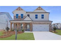 Beautiful two-story home featuring a brick and white facade, a covered porch, and a two-car garage at 3941 Adler Cir, Buford, GA 30519