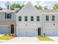 Charming townhome featuring a brick and white painted facade, a one car garage, and well-maintained landscaping at 4671 Larkfield Way, Powder Springs, GA 30127