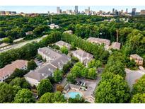 Scenic aerial view of an apartment complex with a pool surrounded by lush greenery and the city skyline in the background at 2700 Pine Tree Ne Rd # 1117, Atlanta, GA 30324