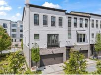 Charming three-story townhouse with painted white brick, a two car garage, and balcony at 215 Arizona Ne Ave # 1, Atlanta, GA 30307