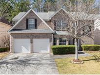 Charming two-story brick home with a two-car garage and well-maintained landscaping and a walkway to the front door at 1973 Tulip Petal Rd, Auburn, GA 30011