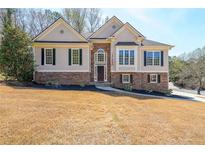 Charming home featuring beige siding accented by stacked stone, complemented by a well-manicured lawn at 2037 Castlemaine Circle, Woodstock, GA 30189