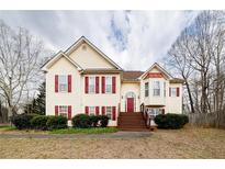 Charming two-story home featuring red shutters, yellow siding, a front porch, and manicured landscaping at 4020 F A A Rd, Cumming, GA 30041