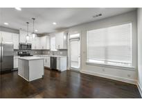 Modern kitchen features stainless steel appliances, white cabinets, a center island, and dark hardwood floors at 5350 Brooklands Dr, Lithonia, GA 30058