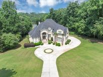 Stunning two-story home with a circular driveway and lush landscaping, surrounded by mature trees offering a secluded feel at 4233 Sandstone Shores Dr, Stonecrest, GA 30038