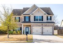 Charming two-story home with brick and siding, two-car garage, and well-manicured front yard at 2436 Planters Mill Way, Conyers, GA 30012