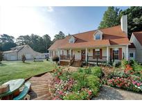 Charming home featuring a landscaped front yard with a covered porch and red shutters at 2585 Braselton Hwy, Buford, GA 30519