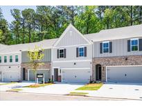 New townhome exteriors showcasing brick accents, attached garages, and professionally landscaped lawns in a suburban neighborhood at 1612 Ruskin Way, Marietta, GA 30062